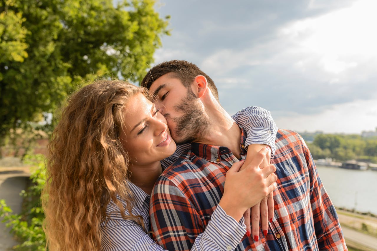 about-me Happy couple sharing a loving embrace outdoors with a scenic background.